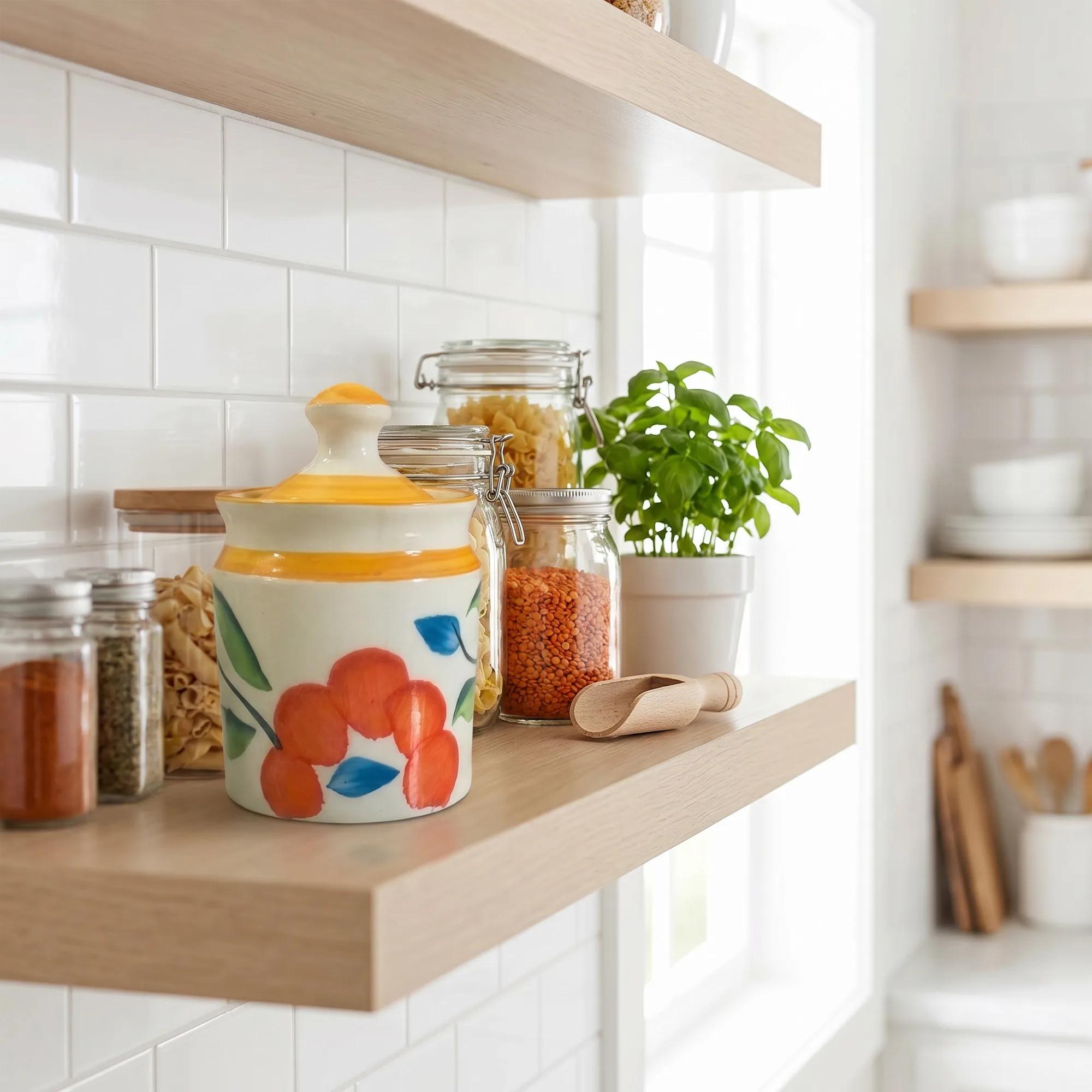 Floral ceramic storage jar placed on a modern kitchen shelf next to other pantry items and a basil plant.