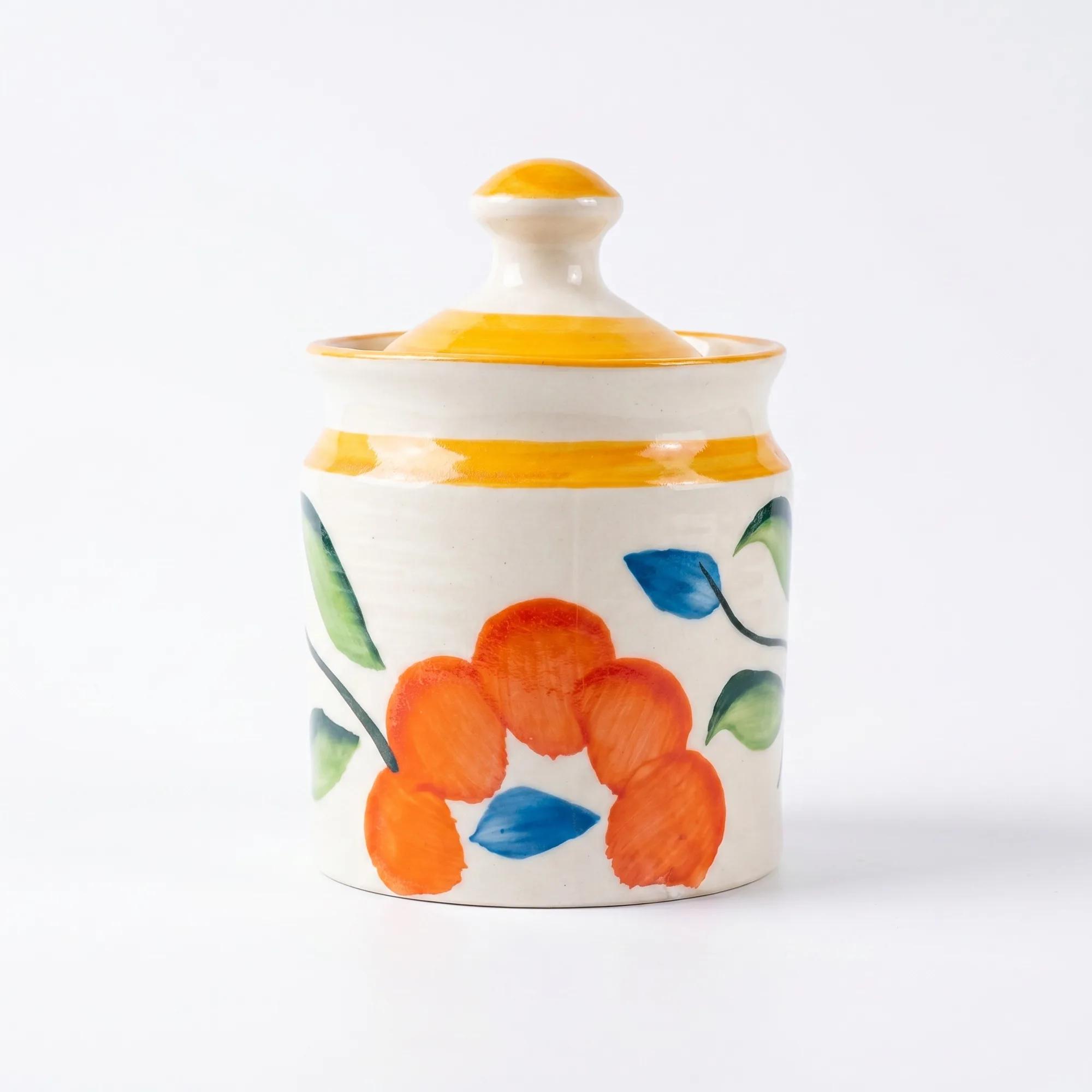 Front view of a single floral ceramic storage jar with a yellow lid against a plain white background.